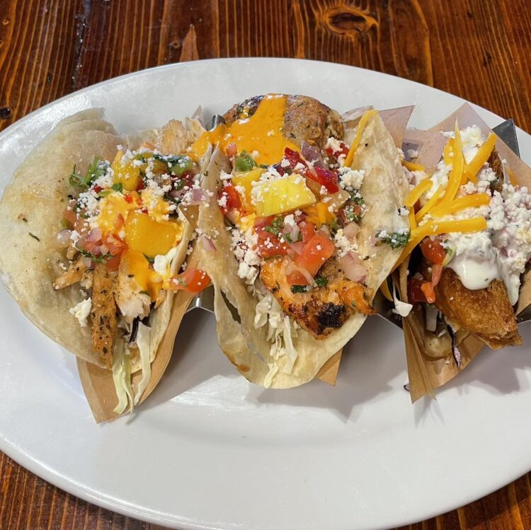 3 Fish tacos topped wsith manog salsa and mexican cheese