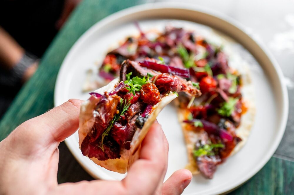 Close-up,Of,A,Hand,Holding,A,Taco,Filled,With,Meat,