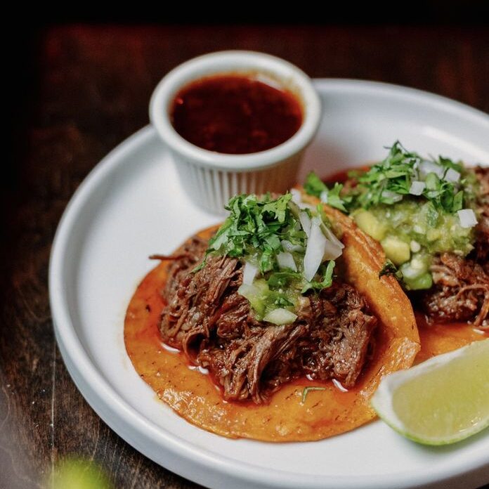 2 Tacos De Birria Tender beef stew slow-cooked in beef broth with Mexican spices and chilies topped with onions, tomatillo sauce, and cilantro