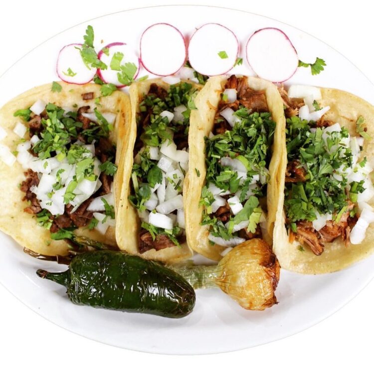 4 carnitas tacos on white plate
