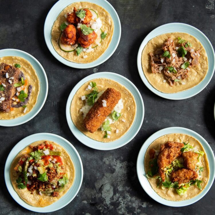 Variety of tacos on small plates on black background