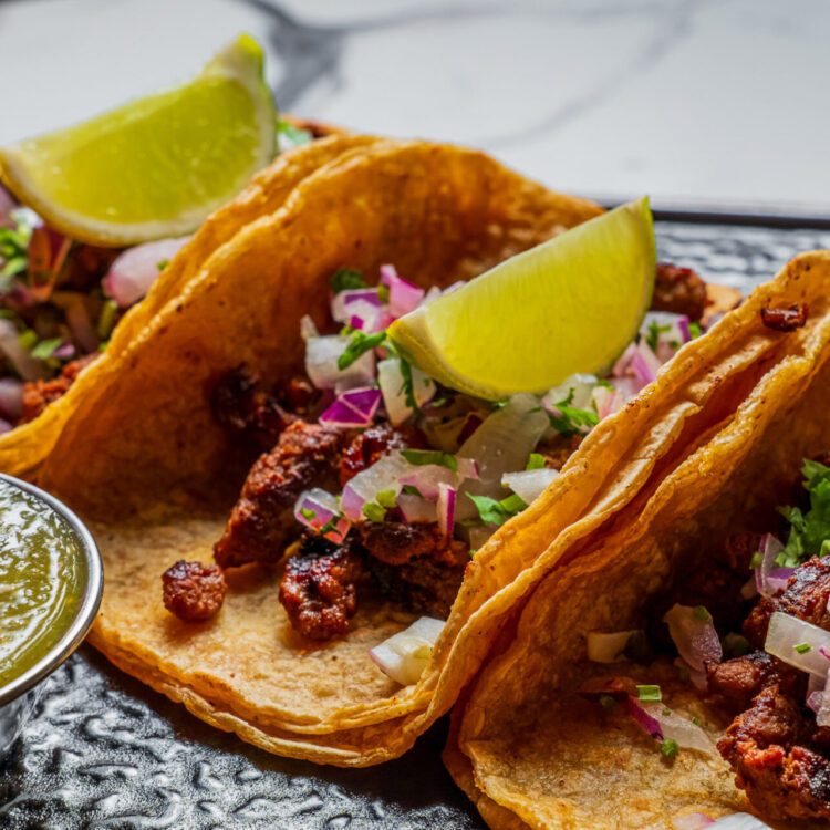 3 asada street tacos with lime wedges