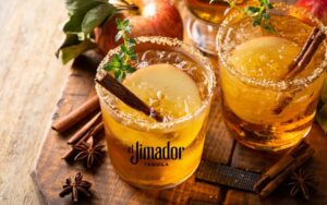 Featured Cocktail - Apple Cider & Maple Margarita - header - photo of two apple cider & maple margaritas on a wooden plank