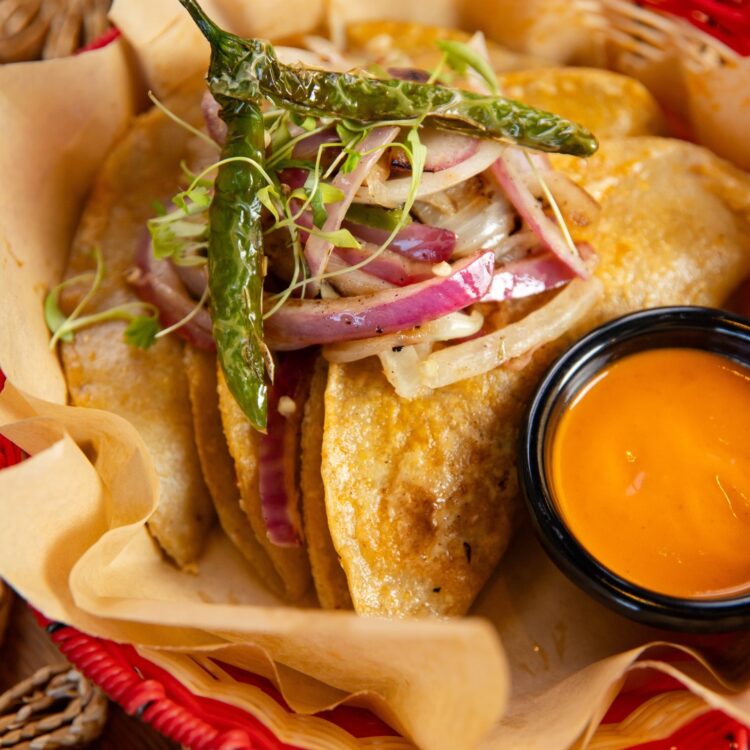Tacos de Canastathree chilorio pork tacos topped with caramelized onions fresh cilantro and a rich red sauce all wrapped in housemade tortillas
