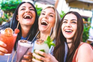 Happy,Young,Friends,Drinking,Cocktails,Outdoors,At,Bar,Garden-,Three
