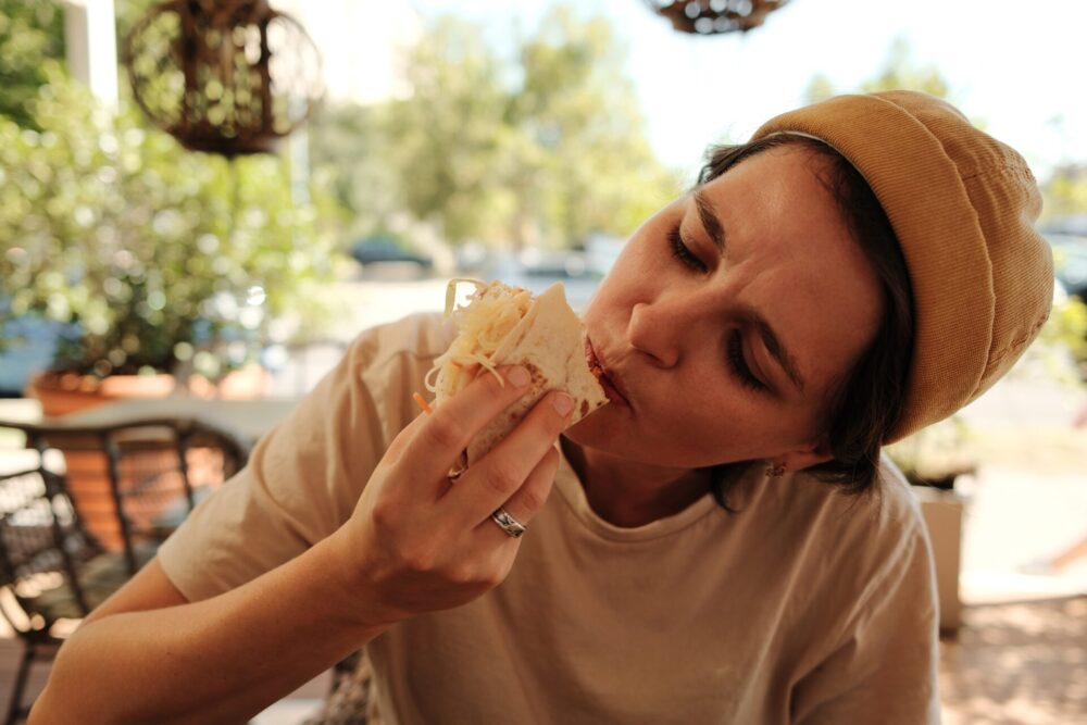 Woman,Enjoying,A,Big,Bite,Of,Cheesy,Taco,At,Mexican