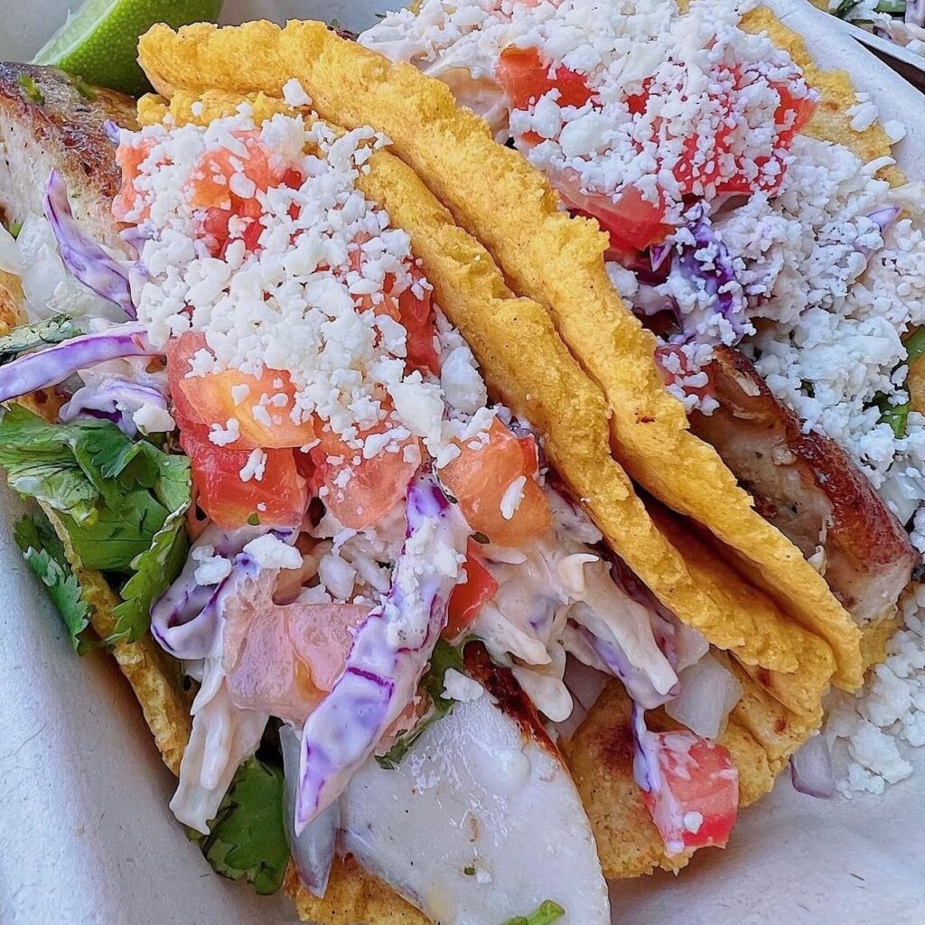Colorful taco salad with crispy yellow shells, diced tomatoes, purple cabbage, lettuce, cilantro, and crumbled white cheese on top.